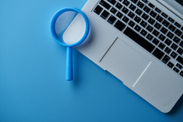 dummy small keyboard and magnifying glass on blue background