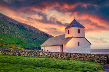 Fototapeta premium Stunning summer view of medieval Olaf's Church in Kirkjubour village. Great sunrise in Faroe Islands, Denmark, Europe. Calm morning scene of Hestur Island. Traveling concept background.