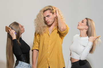 Diverse group of women and man combing hair isolated over background. Attractive cheerful sexy, fashionable group models combing hair. Hairdresser combing hair of attractive man and woman.