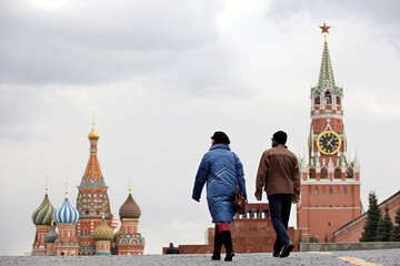 Couple of tourists walking on Red square in Moscow. View to domes of St. Basil's Cathedral and...
