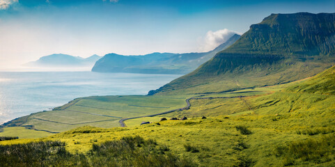 Misty summer view of Faroe Islands with winding country road. Splendid morning scene of outskirts of Sydradalur village, Streymoy island, Denmark, Europe. Traveling concept background..