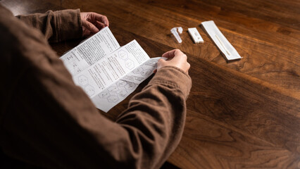 Fototapeta premium close up of a person reading manual of Coronavirus Covid-19 antigen self test kit