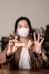 Close up of Asian woman holding the antigen covid test kit happily, showing negative result	