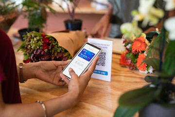 Woman paying florist using mobile phone application to scan QR code