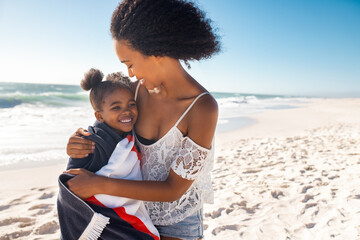 Lovely black woman hugging child with towel at beach - Powered by Adobe