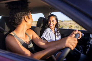 Smiling multiethnic woman friends enjoying road trip in car