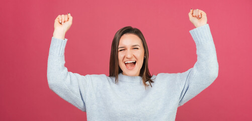 Panorama young winner woman is gesturing with arms up while screaming.