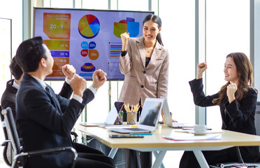 Happy excited cheerful Asian professional successful businessman businesswoman team colleagues in formal suit sitting standing in meeting room holding fists up celebrating job achievement together