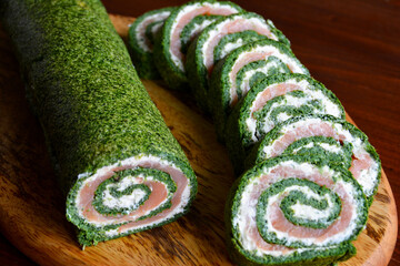 Spinatrolle mit Lachs und Frischkäse auf einem Holzbrett