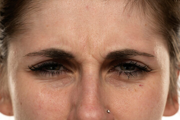 Naklejka premium Angry face of a young woman with facial wrinkles closeup