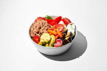 Salad with tuna, vegetables and feta cheese in bowls on a white background. Hard shadows.