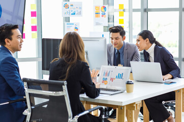 Asian young professional successful businesswoman and businessman employee in formal suit sitting at working desk negotiating discussing with unrecognizable male and female customers in meeting room