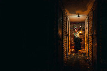 The girl in traditional, national clothes, a wreath with flowers on her head. In hands holds an old...