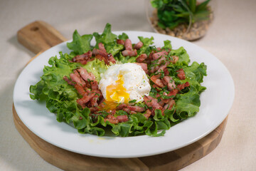 Recipe for poached egg cut with a knife, bacon and salad, High quality photo