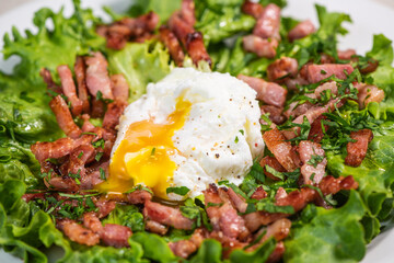 Recipe for poached egg cut with a knife, bacon and salad, High quality photo
