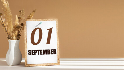 september 1. 1th day of month, calendar date.White vase with dead wood next to cork board with numbers. White-beige background with striped shadow. Concept of day of year, time planner, autumn month