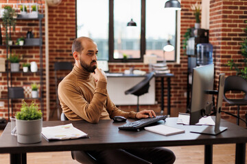 Development department team leader researching investment ideas and business solutions. Startup project manager analyzing financial data and startup management plan while in office workspace.