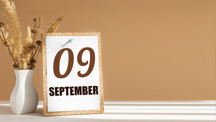 september 9. 9th day of month, calendar date.White vase with dead wood next to cork board with numbers. White-beige background with striped shadow. Concept of day of year, time planner, autumn month