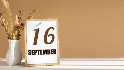 september 16. 16th day of month, calendar date.White vase with dead wood next to cork board with numbers. White-beige background with striped shadow. Concept of day of year, time planner, autumn month