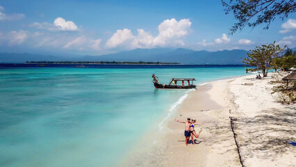 A couple standing on white sand beach on Gili Air, Lombok, Indonesia. Beautiful and clear sea...