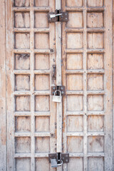 Ancient wooden door with iron padlock. Traditional door in Stone town, Zanzibar. Home security concept. Grunge old doorway with rusty lock. Weathered door with knocker. Closed home entrance.