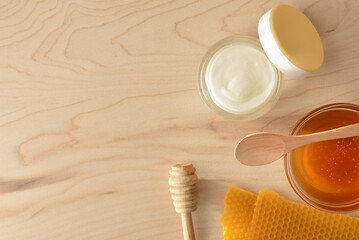 Moisturizing skin care cream with honey extracts on wooden table