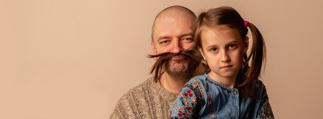 Father and daughter have fun. They are playing with hair of young child girl. Copy space.