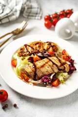 Grilled chicken fillet with vegetables in a white plate on a light gray culinary background. Dietary poultry breast on the kitchen table closeup	