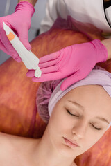 Relaxed woman waiting while professional beautician applying cream hydtration mask