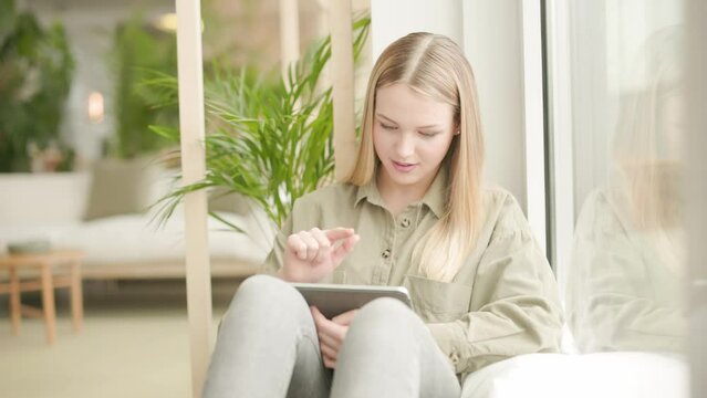 Young woman using digital tablet looking out of window