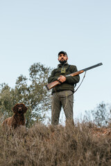 Portrait of man holding his shotgun with his dog next to him