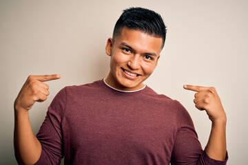 Young handsome latin man wearing casual sweater standing over isolated white background looking...