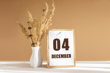 december 4. 4th day of month, calendar date.White vase with dried flowers on desktop in rays of...