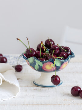 Sweet Cherries In A Small Vase On A White Table