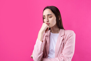Portrait of beautiful young woman in pink jacket thinking isolated on red background