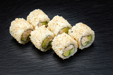 Traditional delicious fresh sushi roll set on a black background. Sushi roll with rice, cream cheese, avocado, salmon, sesame. Philadelphia. Sushi menu. Japanese kitchen, restaurant.