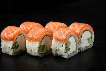 Philadelphia roll sushi with salmon, cucumber and cream cheese on black background for menu. Japanese food