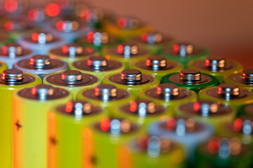 Closeup of positive ends of discharged batteries AA sizes, macro shot, selective focus. Used alkaline battery. Hazardous garbage concept. Neon yellow light