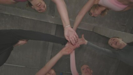 bottom view of a group of female sportswomen in circle huddling and joining hands to express unity
