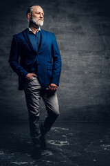 Fototapeta premium Elegant old man dressed in dark blue jacket against dark background