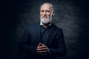 Cheerful aged man dressed in dark jacket against dark background