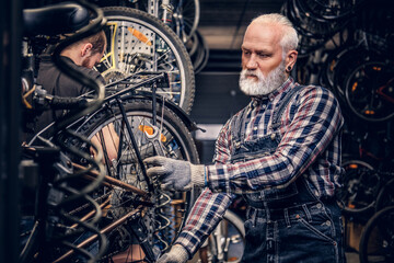 Obraz premium Grandfather and grandson repairing bicycles together in workshop