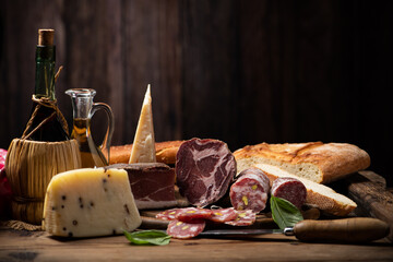 Fototapeta na wymiar Cutting board with ham, salami, cheese, bread on a rustic wooden board