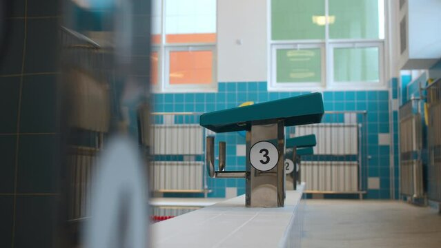 Posts with numbers on swimming pool edge at contemporary sports complex. Space and equipment for sportsmen development