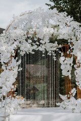 Front view of fashion trendy arch decorated with fresh flowers and other decor. Concept of wedding ceremony details.