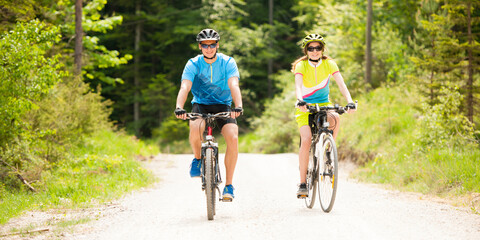 active Young couple biking on a forest road in mountain on a spring day	 - 496268736