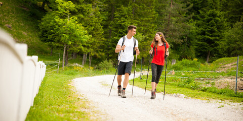 active Beautiful young couple hiking ina nature climbing hill or mountain - man and woman trekking - 496268767