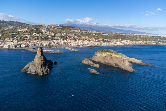 Sea stacks off Acitrezza with Mt Etna in distance, Catania, Sicily, Italy