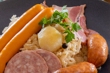 close-up Choucroute garnie (French for dressed sauerkraut) is an Alsatian recipe for preparing sauerkraut with sausages and other cured meats and charcuterie, and often potatoes.
