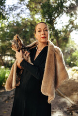 Mature posh woman looking at the camera while holding her puppy